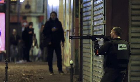 epa05023916 A French police officer takes cover while on the lookout for the shooters who attacked the restaurant 'Le Petit Cambodge' earlier tonight in Paris, France, 13 November 2015. At least 60 people have been killed in a series of attacks in the French capital Paris, with a hostage-taking also reported at a concert hall. EPA/ETIENNE LAURENT