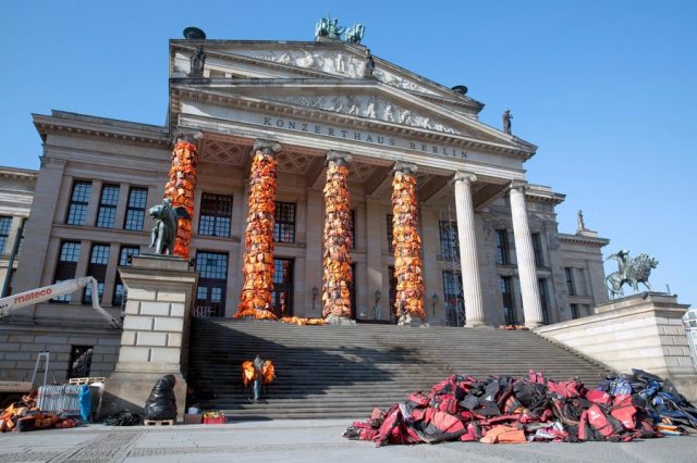epa05158089 A general view shows workers attaching life vests to the Berlin's concert hall as part of an art action in Berlin, Germany, 13 February 2016. Chinese artist Ai Weiwei wants to draw attention to the fate of many refugees who have drowned on their way to Europe. Weiwei got the life vests from the Greek island of Lesbos.   EPA/JOERG CARSTENSEN