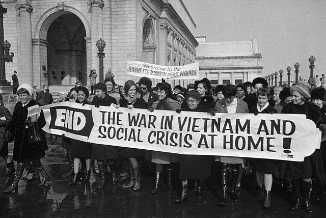 A group of women belonging to the Jeanette Rankin Brigade march in protest of the Vietnam War.  Jeanette Rankin, the first female congress member, stands holding the banner at center (wearing eyeglasses). January 15, 1968 Washington, DC, USA